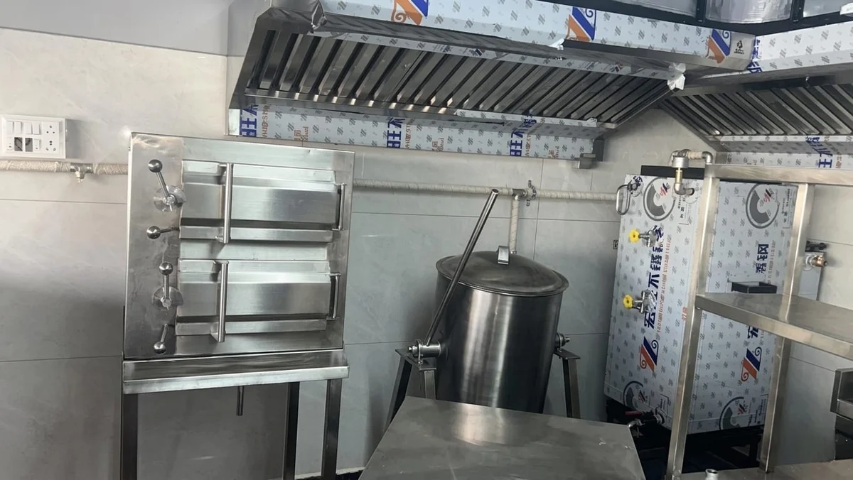 Commercial steam cooking equipment and tilting vessel below a kitchen exhaust hood